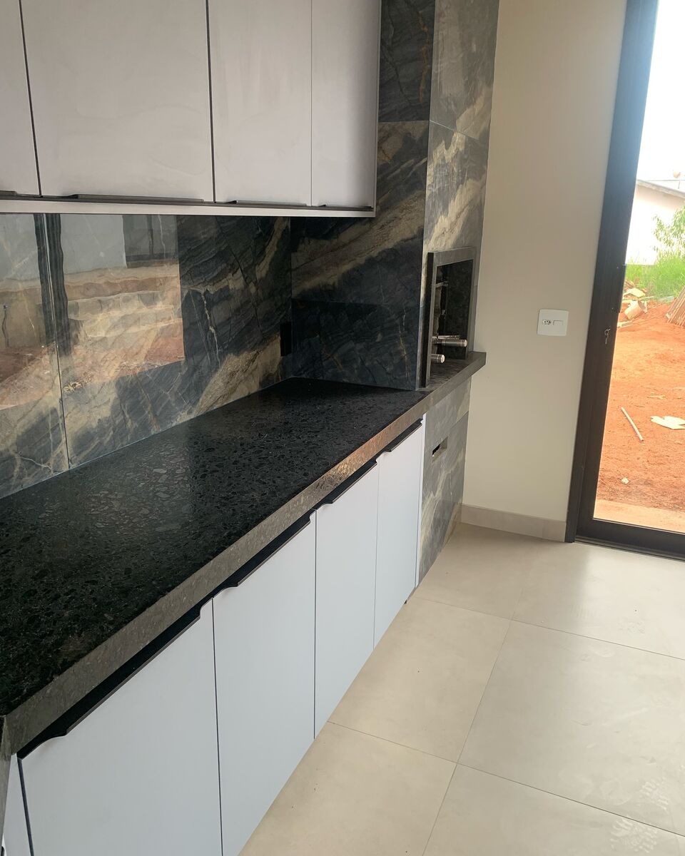 Bancada e revestimento em granito escuro na cozinha