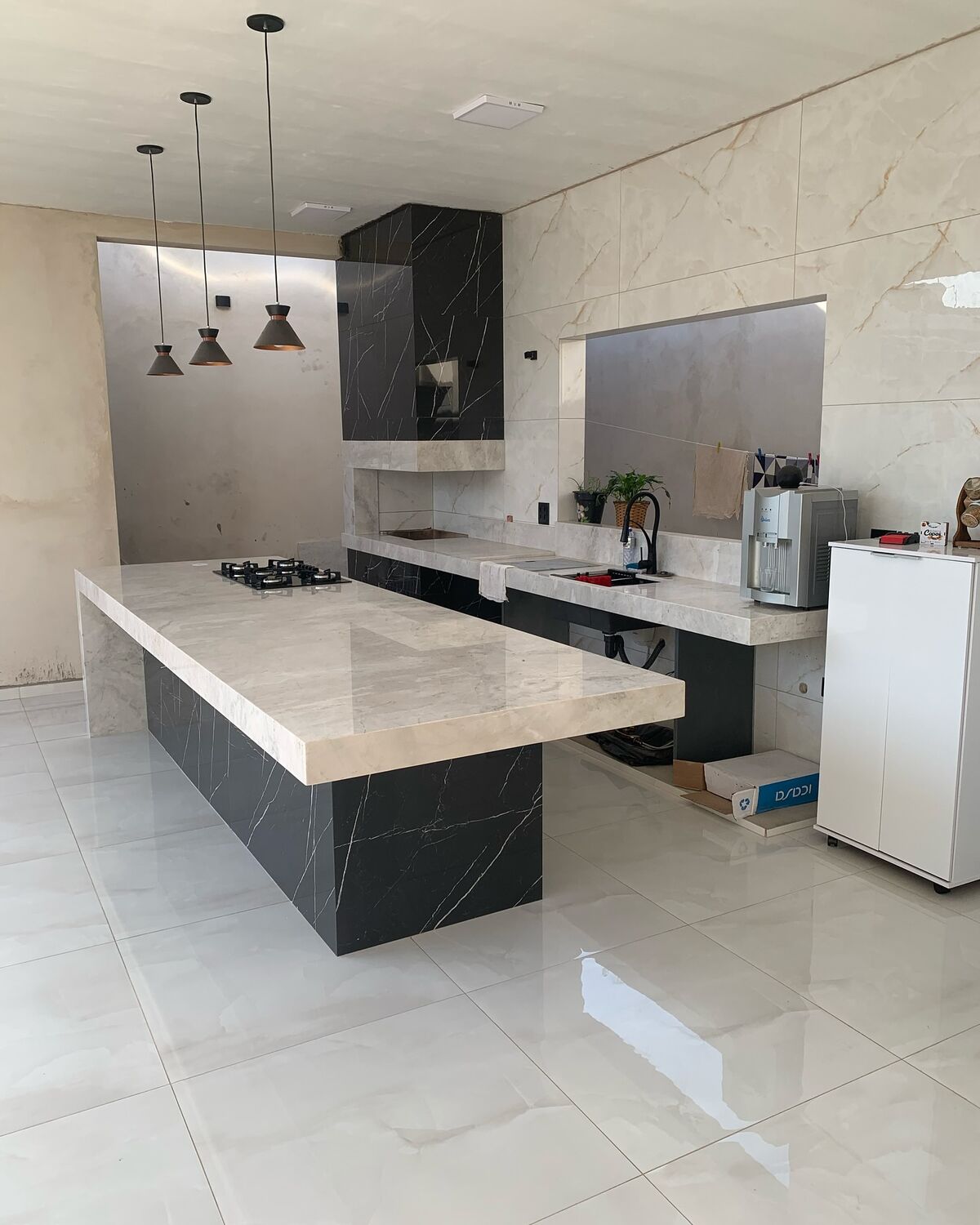 Cozinha com ilha em pedra escura e tampo claro